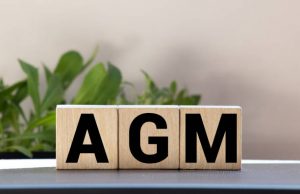 AGM Annual general meeting acronym on wooden cubes on blue backround. Business concept.